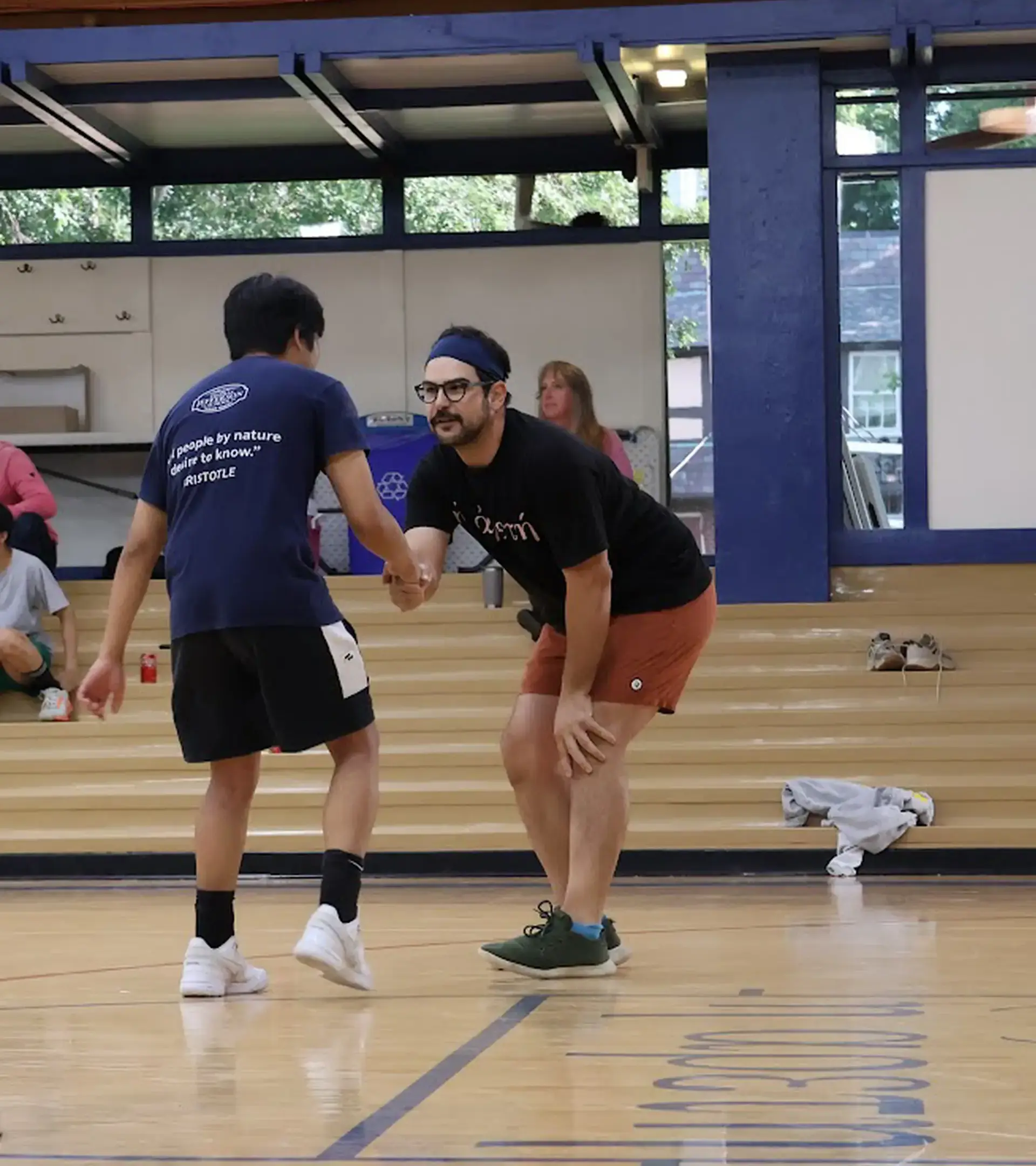 A student and faculty member celebrating sportsmanship and team spirit during a game or activity inside the school gymnasium.