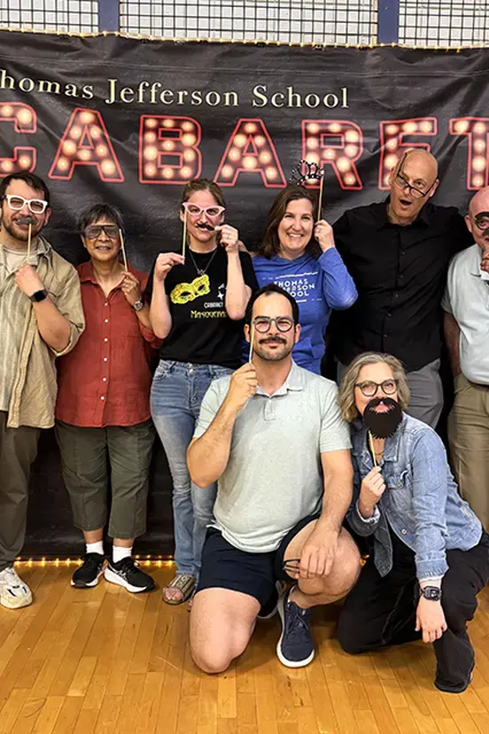 A diverse group of teachers and students smiling and posing together in a gymnasium.