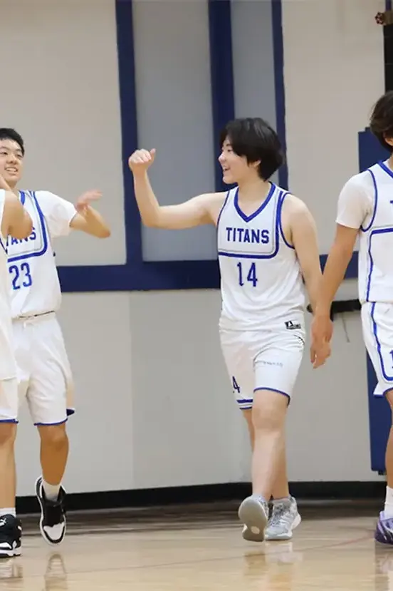 basketball players in white uniforms high-fiving on the court during a game.